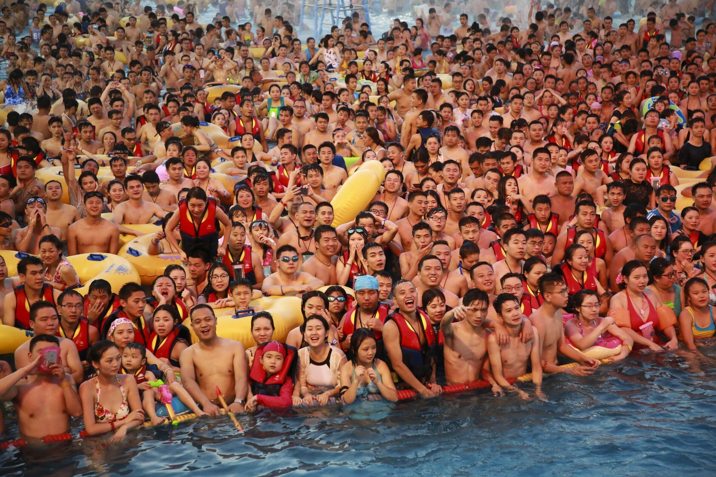 Сколько человек купается. Переполненный бассейн в Китае. Много людей в бассейне. Много людей на пляже. Куча народу в бассейне.